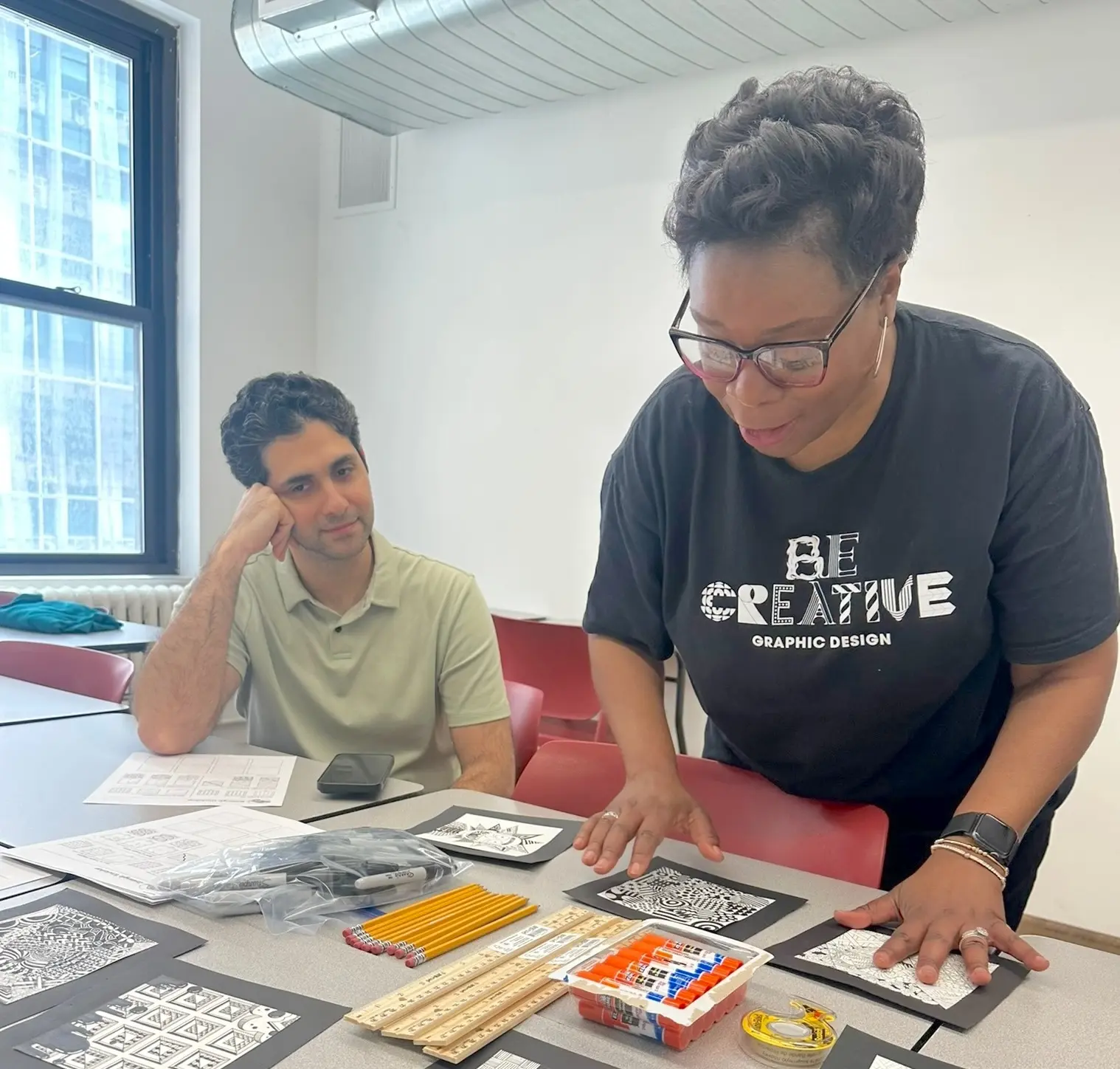 Graphic design instructor presenting student Zentangle artwork during a hands-on workshop for Rennert students.